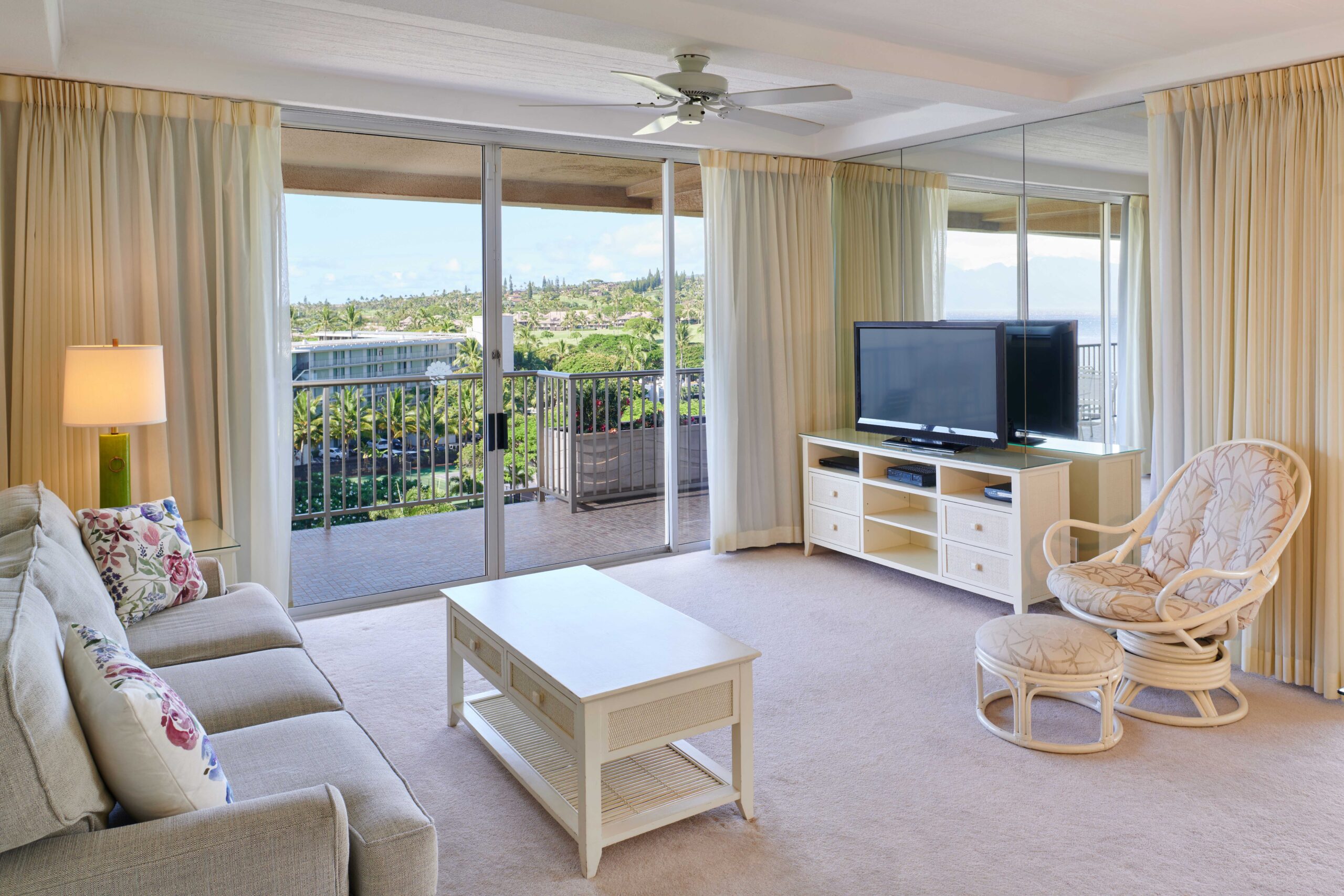 1-bedroom / 2-bath Ocean View Suite living area with couch, coffee table, TV with entertainment stand, rocking chair, and open balcony