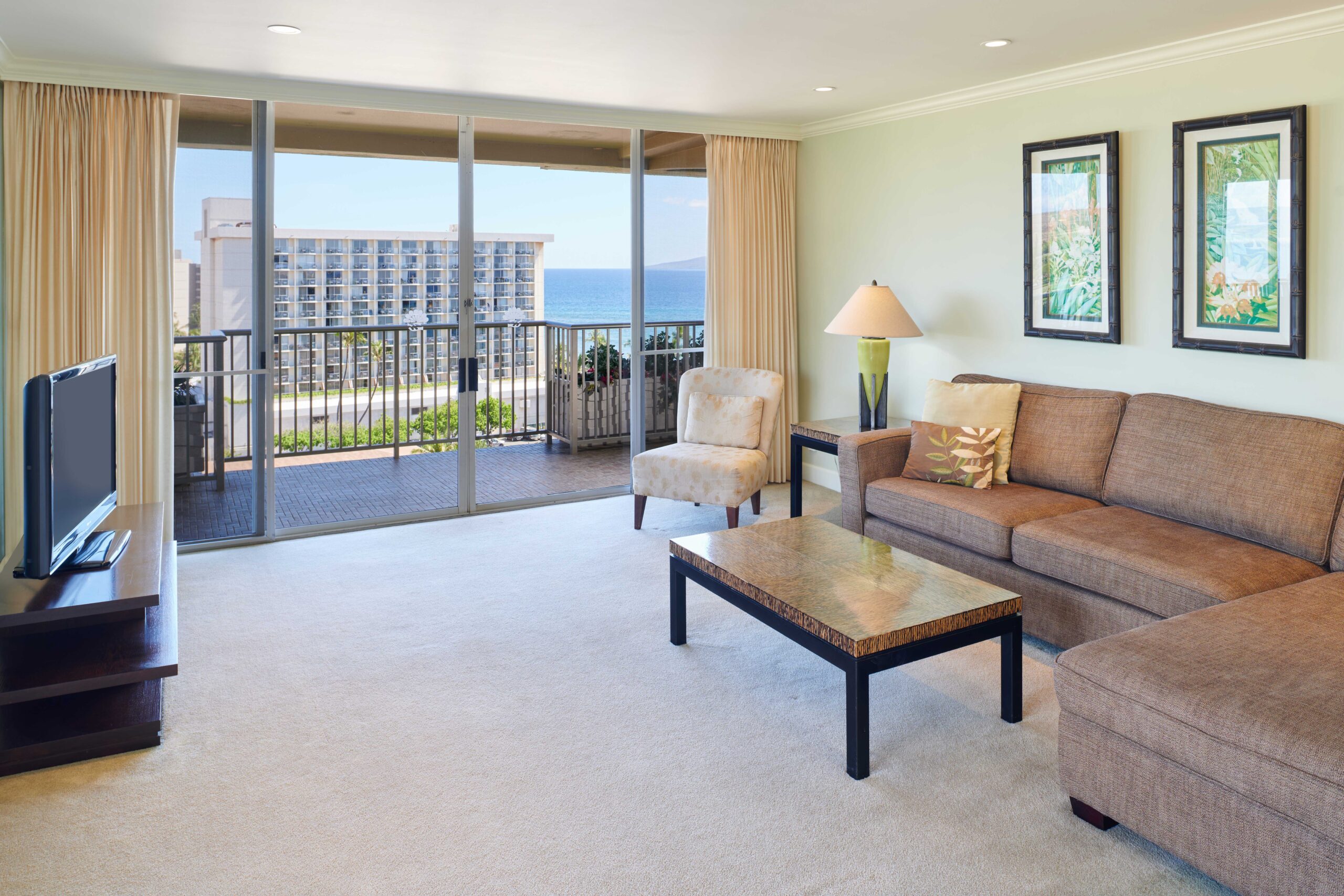 2-bedroom Ocean View Premium Suite living area with coffee table, sectional couch, and TV with open balcony