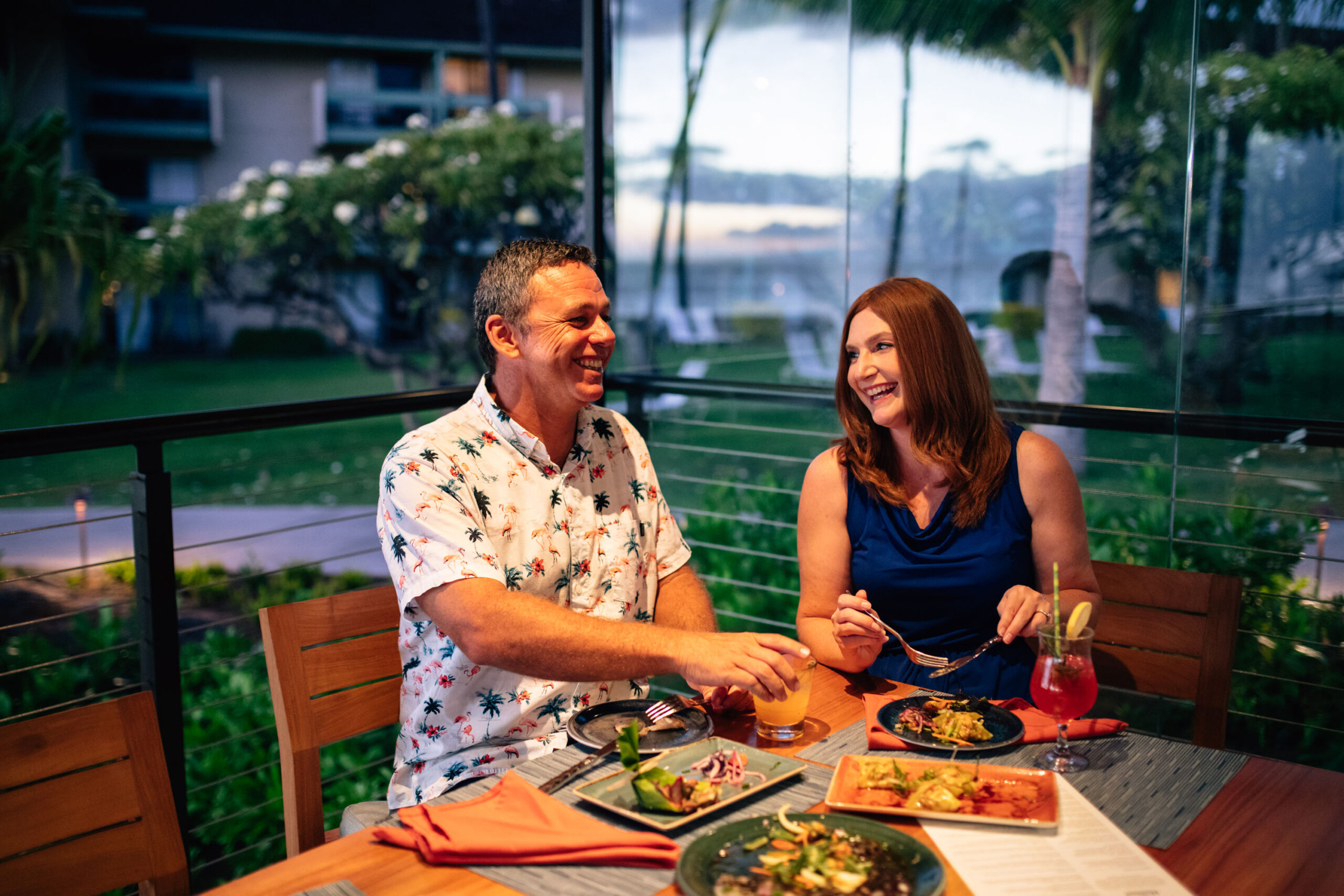 Man and woman sitting at table in restaurant with variety of food dishes