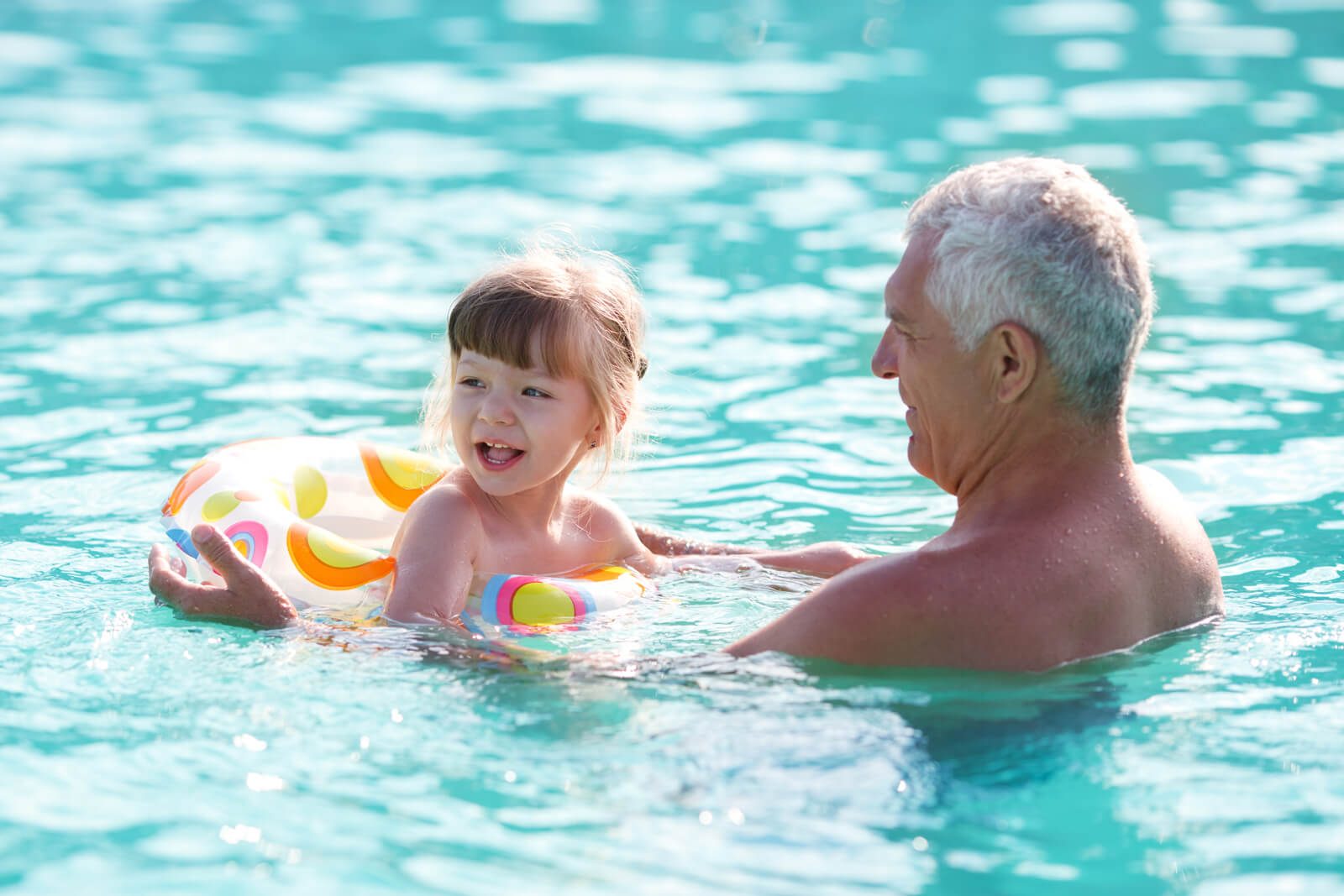 Girl and grandfather in swimming pool.