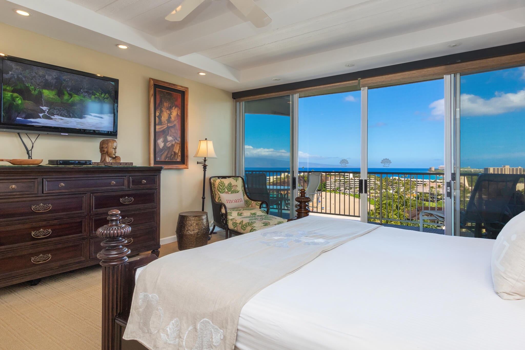 Room with a bed, dresser, TV, and balcony with ocean views.